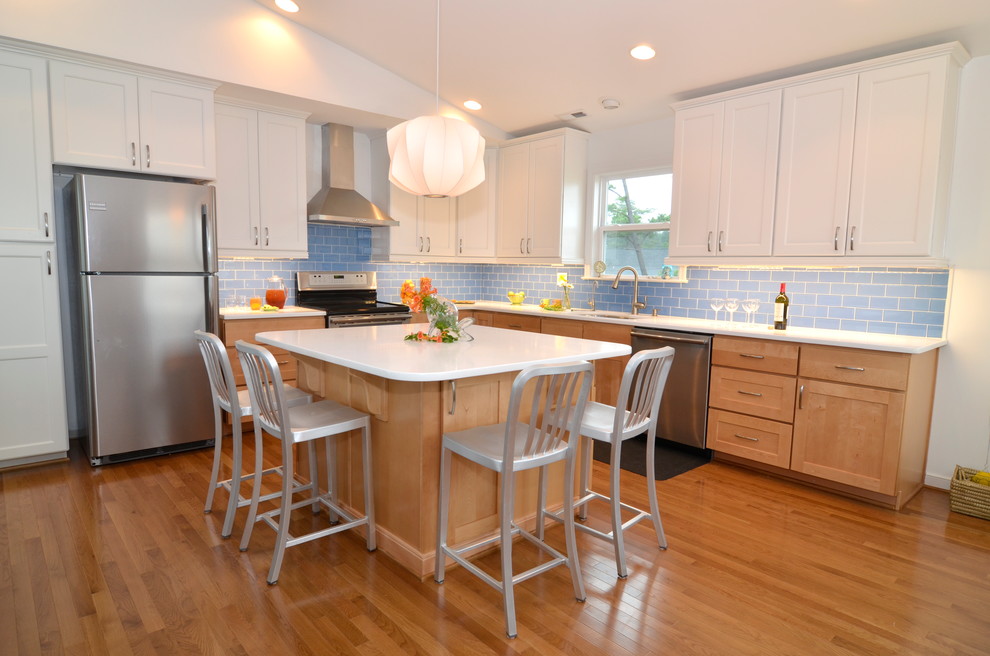 Eat-in kitchen - large transitional l-shaped light wood floor eat-in kitchen idea with shaker cabinets, white cabinets, quartz countertops, blue backsplash, glass tile backsplash, stainless steel appliances, white walls and an island