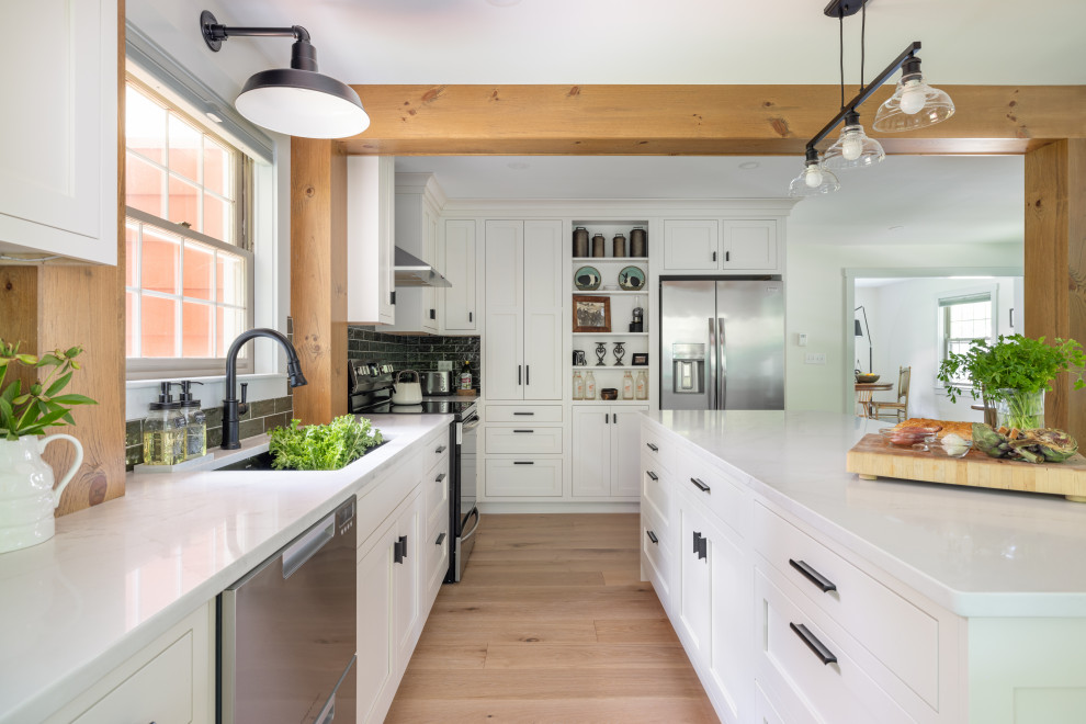 Small french country l-shaped eat-in kitchen photo with a farmhouse sink, shaker cabinets, white cabinets, quartzite countertops, green backsplash, subway tile backsplash, stainless steel appliances, an island and white countertops