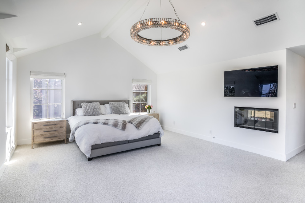 Idée de décoration pour une grande chambre minimaliste avec un mur blanc, une cheminée double-face, un sol gris et un plafond voûté.