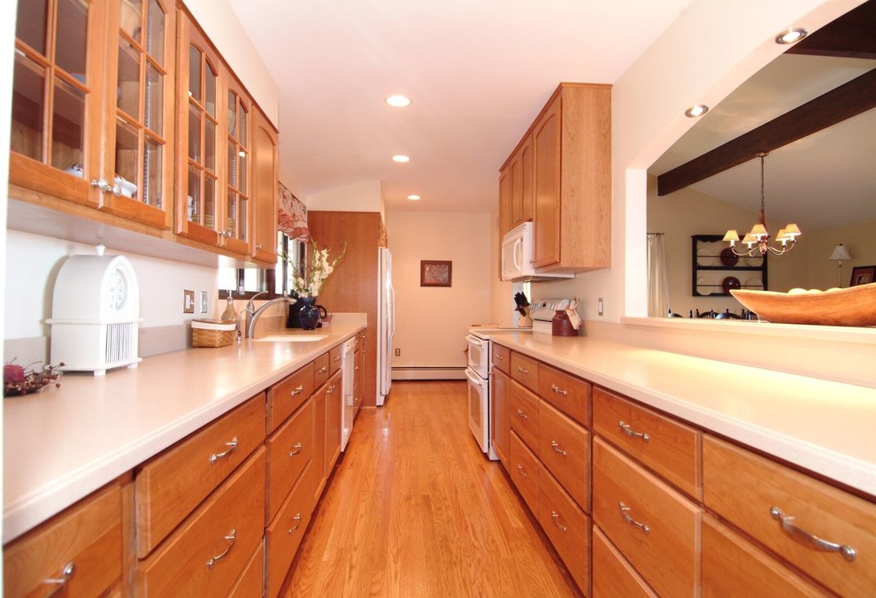 Design ideas for a large traditional galley separate kitchen in DC Metro with an undermount sink, raised-panel cabinets, light wood cabinets, solid surface benchtops, white appliances, light hardwood floors, no island and beige floor.