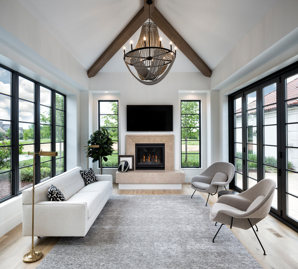 Photo of a mediterranean sunroom in Minneapolis with light hardwood floors, a standard fireplace, a stone fireplace surround and a standard ceiling.