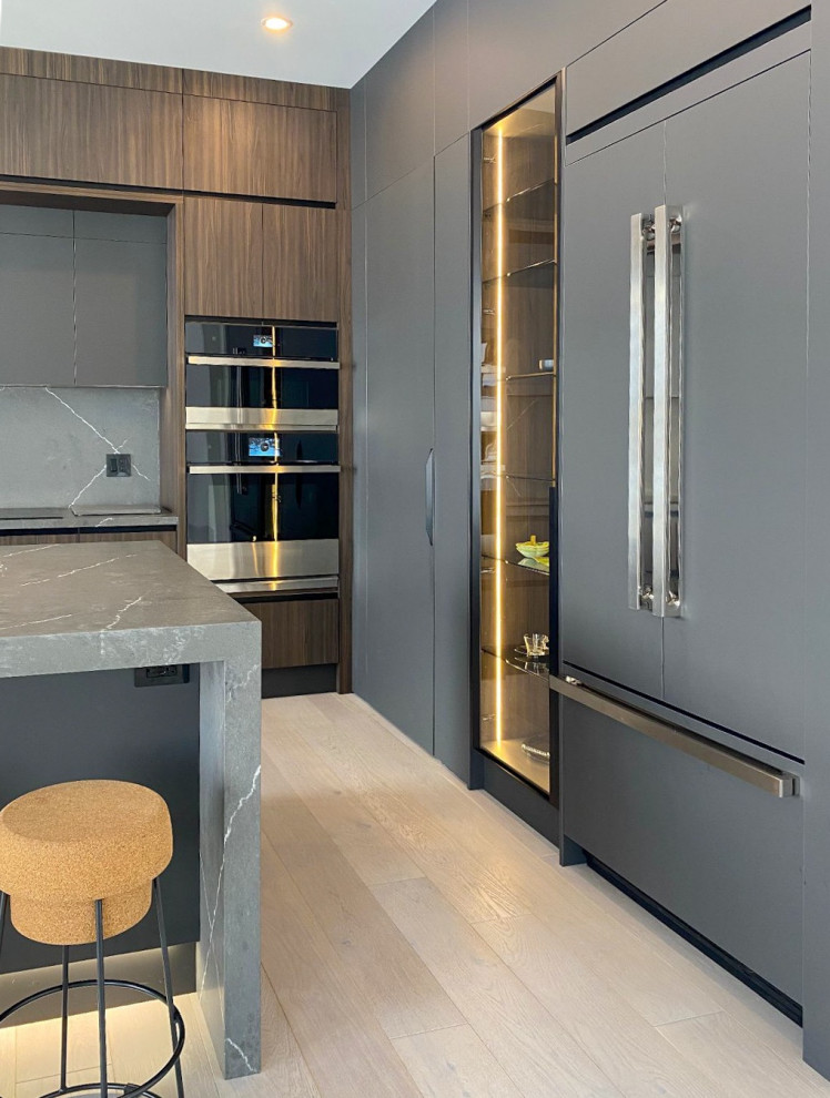 This is an example of a large modern kitchen/diner in Toronto with flat-panel cabinets, engineered stone countertops, grey splashback, engineered quartz splashback, an island, grey worktops, dark wood cabinets and light hardwood flooring.