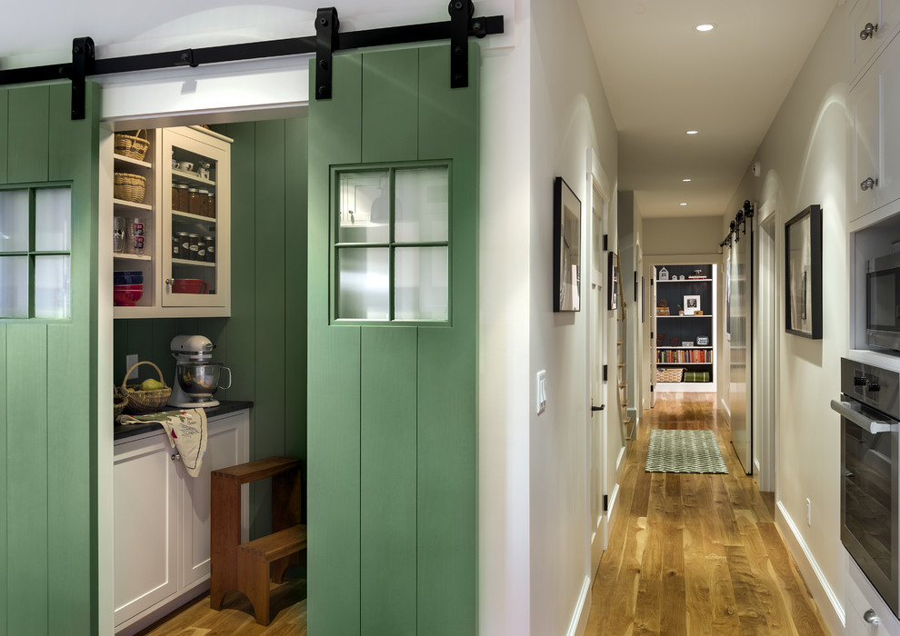 Inspiration for a mid-sized timeless medium tone wood floor hallway remodel in Portland Maine with white walls