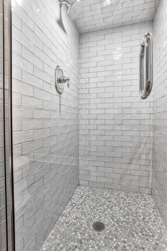 Design ideas for a large traditional bathroom in New York with an alcove shower, a two-piece toilet, gray tile, subway tile, beige walls, medium hardwood floors, a pedestal sink, brown floor and a hinged shower door.