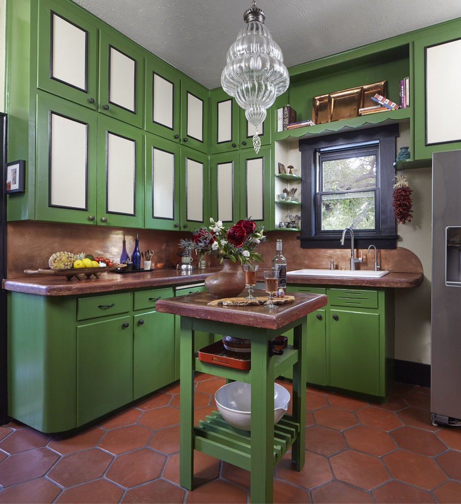 Kitchen - southwestern l-shaped terra-cotta tile and brown floor kitchen idea in Denver with a drop-in sink, flat-panel cabinets, green cabinets, brown backsplash, stainless steel appliances, an island and brown countertops