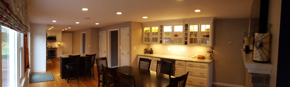 Eat-in kitchen - large transitional l-shaped light wood floor eat-in kitchen idea in Boston with an undermount sink, raised-panel cabinets, white cabinets, granite countertops, gray backsplash, ceramic backsplash, stainless steel appliances and an island