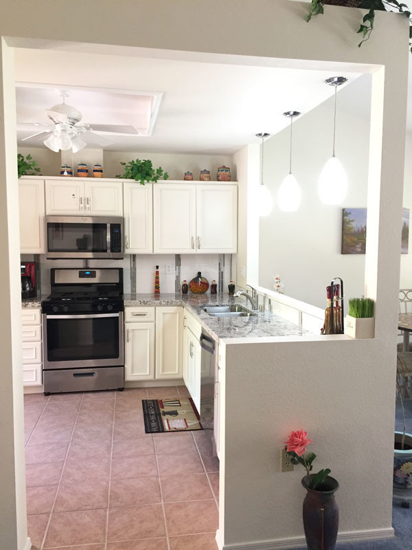 Small transitional l-shaped kitchen pantry in Las Vegas with a double-bowl sink, beaded inset cabinets, white cabinets, quartz benchtops, white splashback, porcelain splashback, stainless steel appliances, porcelain floors, no island and pink floor.