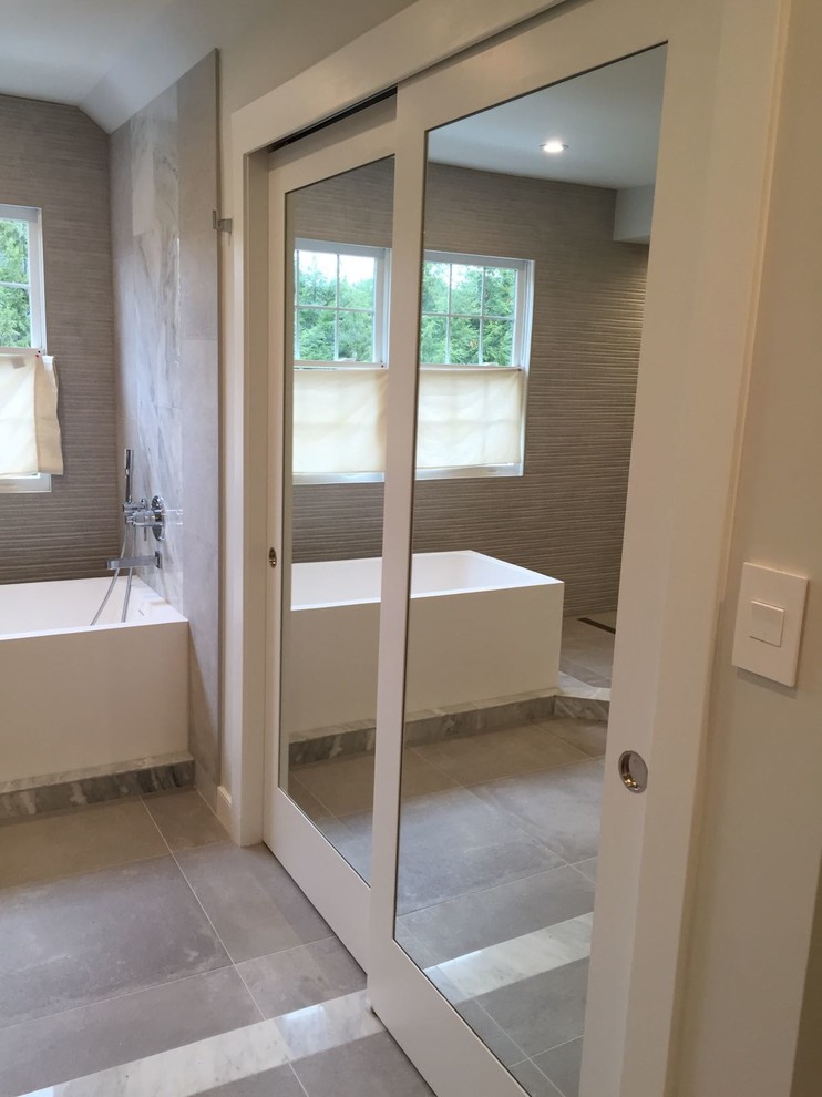 Inspiration for an expansive contemporary master bathroom in DC Metro with flat-panel cabinets, dark wood cabinets, a freestanding tub, an open shower, a one-piece toilet, gray tile, porcelain tile, grey walls, porcelain floors, an undermount sink and engineered quartz benchtops.