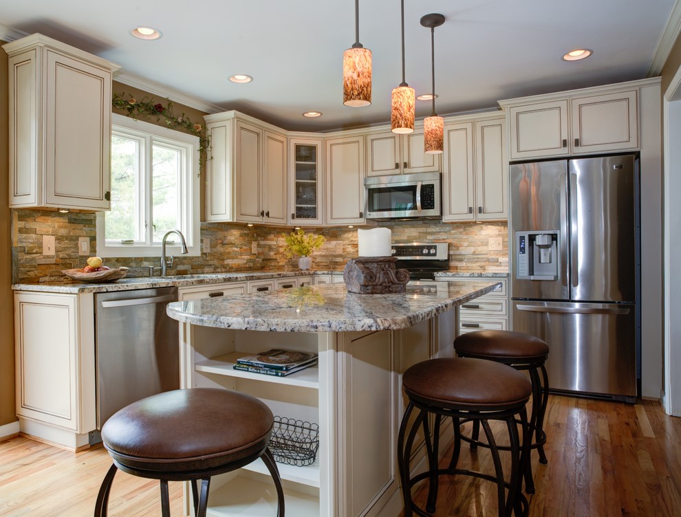 This is an example of a mid-sized country l-shaped open plan kitchen in DC Metro with a drop-in sink, beaded inset cabinets, white cabinets, granite benchtops, multi-coloured splashback, stainless steel appliances, medium hardwood floors and with island.