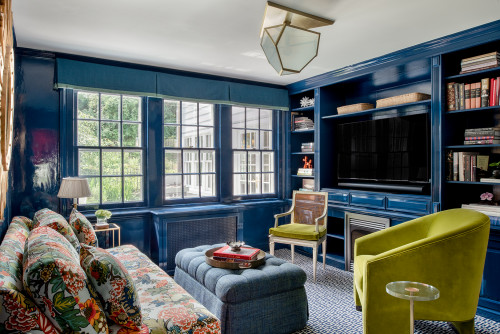 Living room with dark blue paint colour, featuring a couch, chair, and bookshelves.