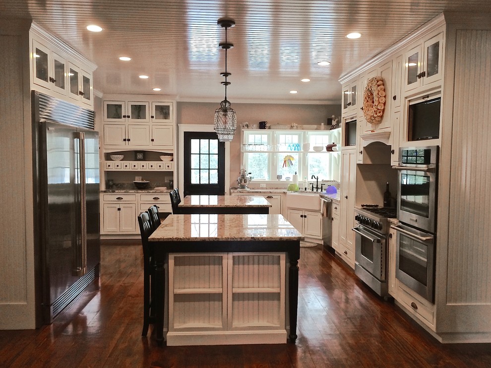 Inspiration for a large country u-shaped eat-in kitchen in Boston with a farmhouse sink, beaded inset cabinets, white cabinets, granite benchtops, stainless steel appliances, dark hardwood floors and multiple islands.
