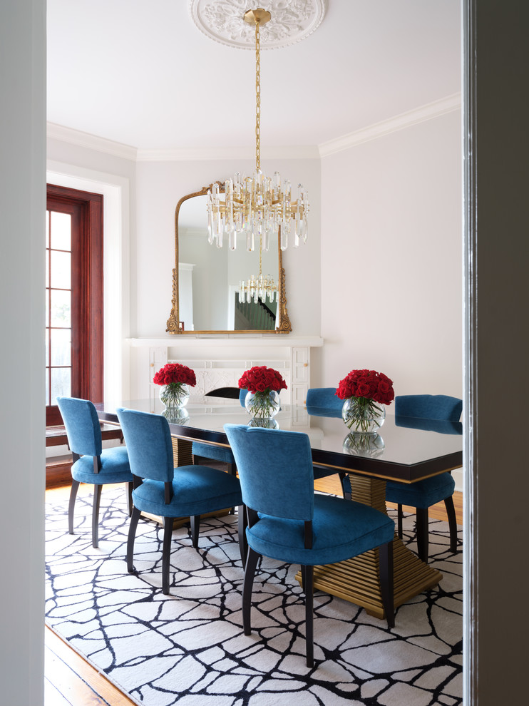 This is an example of a mid-sized transitional separate dining room in DC Metro with white walls, medium hardwood floors, a corner fireplace and a wood fireplace surround.