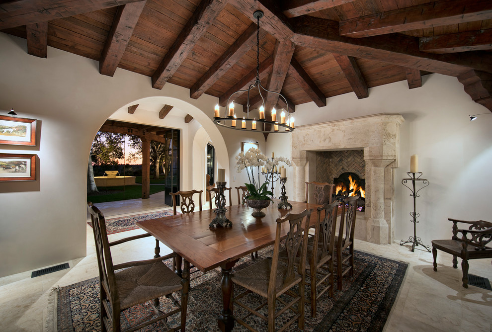 Mediterranean separate dining room in Santa Barbara with white walls, a standard fireplace, a tile fireplace surround and beige floor.