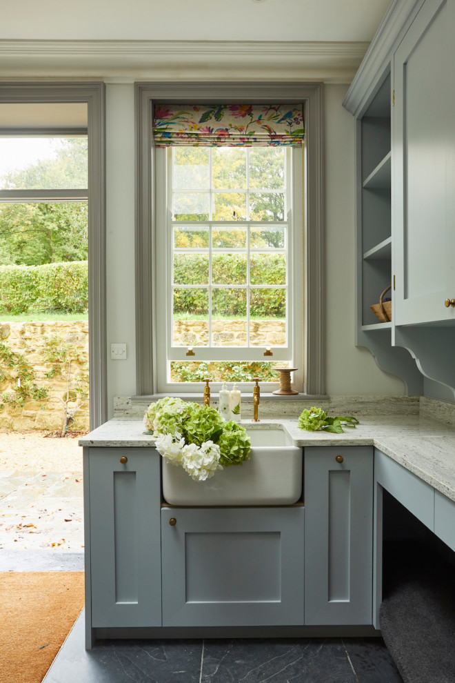 This is an example of a small traditional utility room in Wiltshire with a belfast sink, recessed-panel cabinets, blue cabinets, marble worktops, white splashback, marble splashback, white walls, slate flooring, grey floors and white worktops.