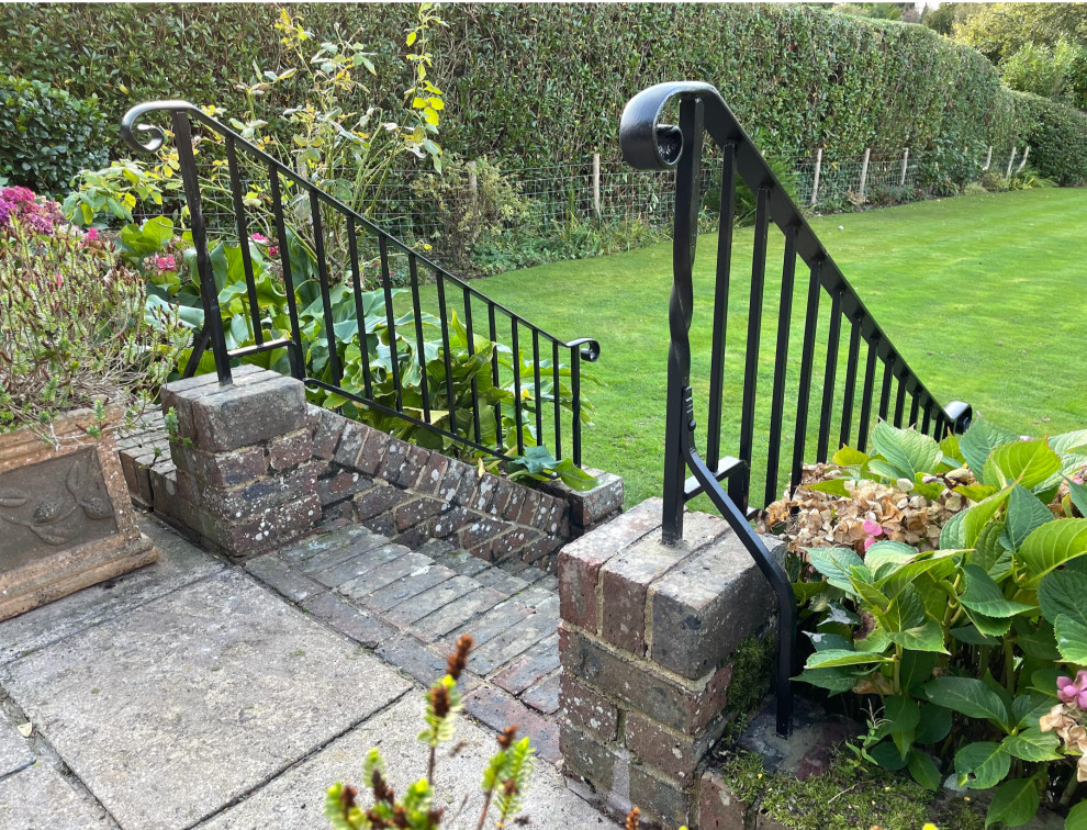 На фото: участок и сад на заднем дворе в классическом стиле с полуденной тенью, мощением клинкерной брусчаткой и с металлическим забором с