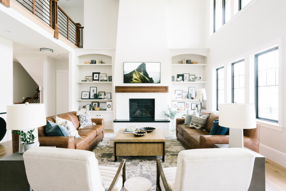 Inspiration for a large transitional open concept family room in Salt Lake City with white walls, light hardwood floors, a standard fireplace, a brick fireplace surround, a wall-mounted tv, brown floor and vaulted.