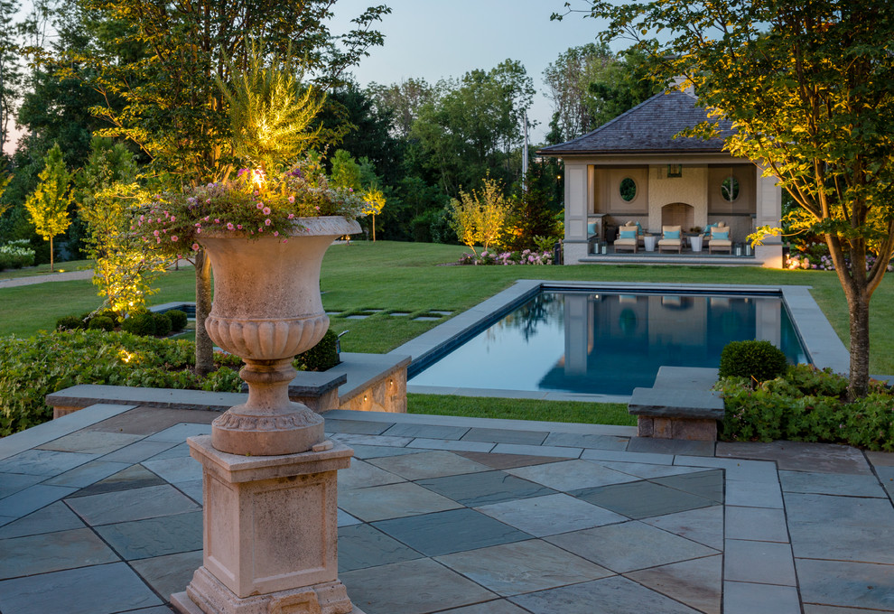 This is an example of a large traditional backyard rectangular pool in New York with a pool house and natural stone pavers.
