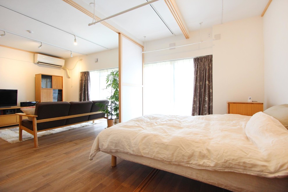 Small scandinavian bedroom in Tokyo with white walls, medium hardwood floors and brown floor.