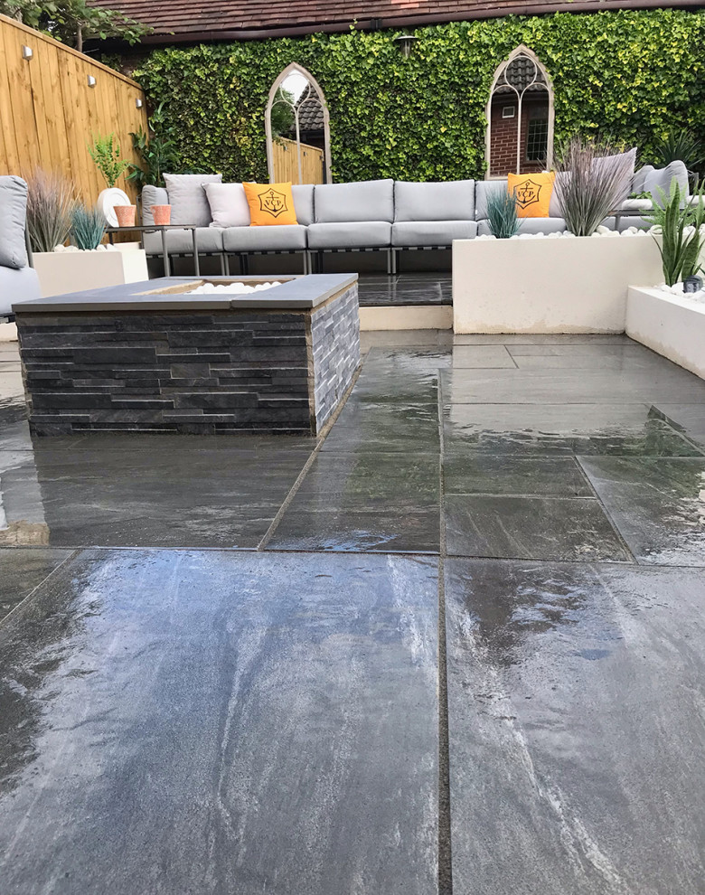 This is an example of a mid-sized contemporary backyard patio in Essex with tile.