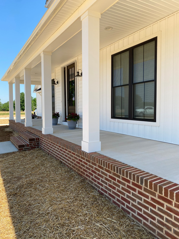 Immagine di un portico country di medie dimensioni e davanti casa con pavimentazioni in mattoni e un tetto a sbalzo