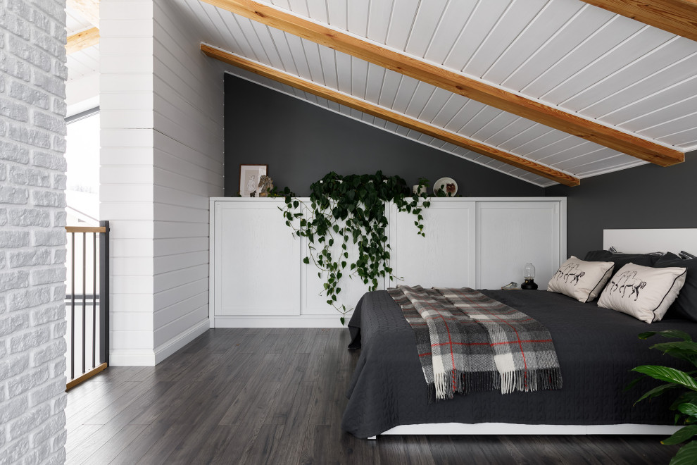Modelo de dormitorio principal y gris y blanco tradicional renovado de tamaño medio con paredes grises, suelo de madera oscura, todas las chimeneas, marco de chimenea de metal, suelo gris, vigas vistas y papel pintado