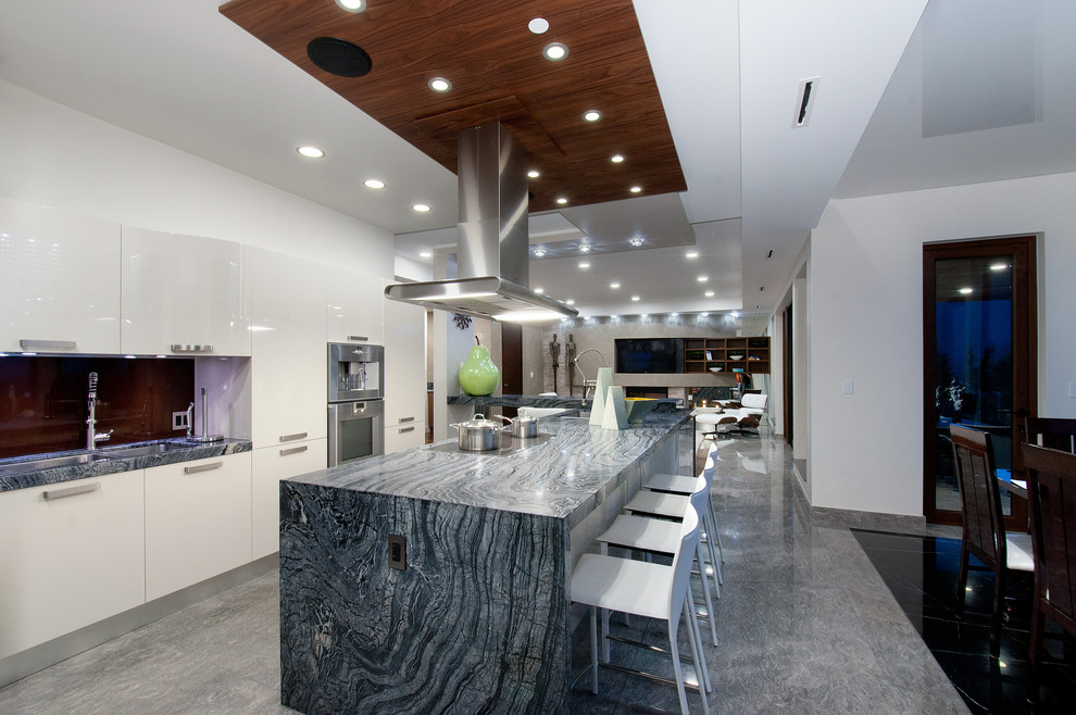 Photo of a contemporary u-shaped open plan kitchen in Vancouver with a double-bowl sink, flat-panel cabinets, white cabinets, marble benchtops, brown splashback, glass sheet splashback and stainless steel appliances.