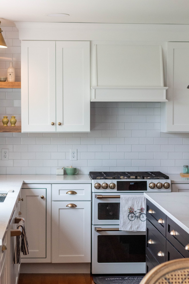 Open concept kitchen - mid-sized transitional l-shaped medium tone wood floor and brown floor open concept kitchen idea with an undermount sink, shaker cabinets, white cabinets, quartzite countertops, white backsplash, ceramic backsplash, white appliances, an island and white countertops