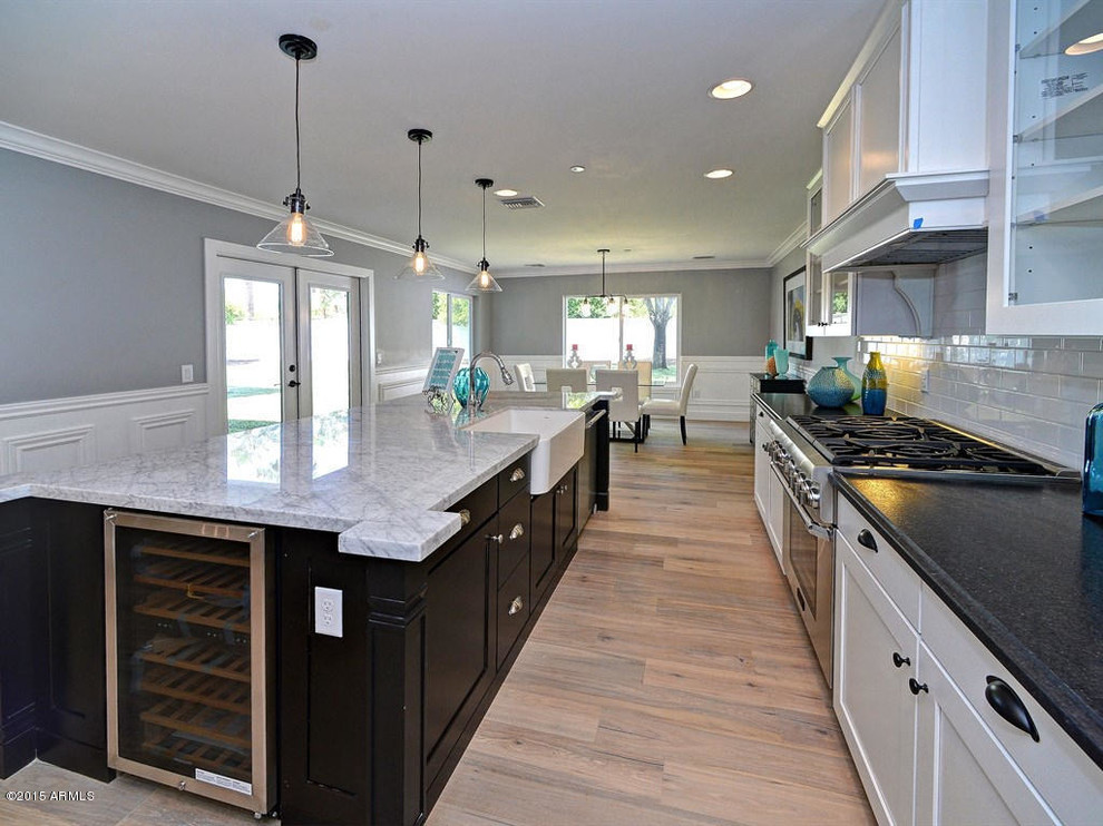 Inspiration for a contemporary l-shaped eat-in kitchen in Phoenix with a single-bowl sink, recessed-panel cabinets, white cabinets, granite benchtops, white splashback, porcelain splashback, stainless steel appliances, light hardwood floors and with island.