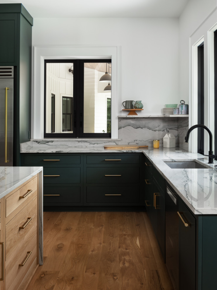 Inspiration for a large country u-shaped kitchen pantry in New Orleans with an undermount sink, flat-panel cabinets, green cabinets, marble benchtops, grey splashback, marble splashback, stainless steel appliances, medium hardwood floors, with island, brown floor and grey benchtop.