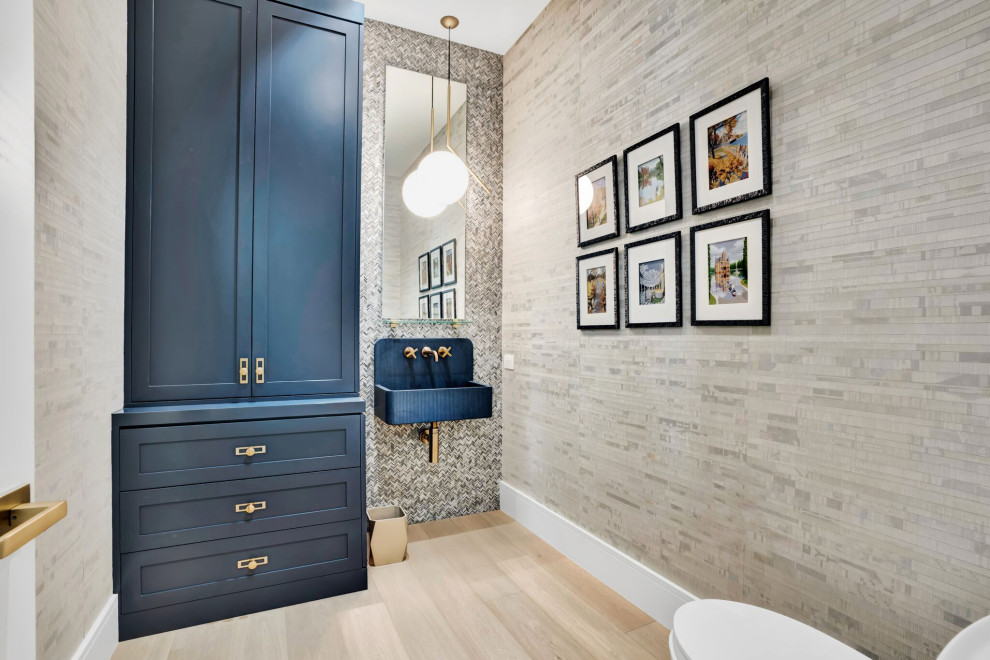 Design ideas for a mid-sized contemporary powder room in Miami with flat-panel cabinets, blue cabinets, a one-piece toilet, beige tile, mosaic tile, beige walls, light hardwood floors, a wall-mount sink, concrete benchtops, beige floor, white benchtops, a floating vanity and wallpaper.