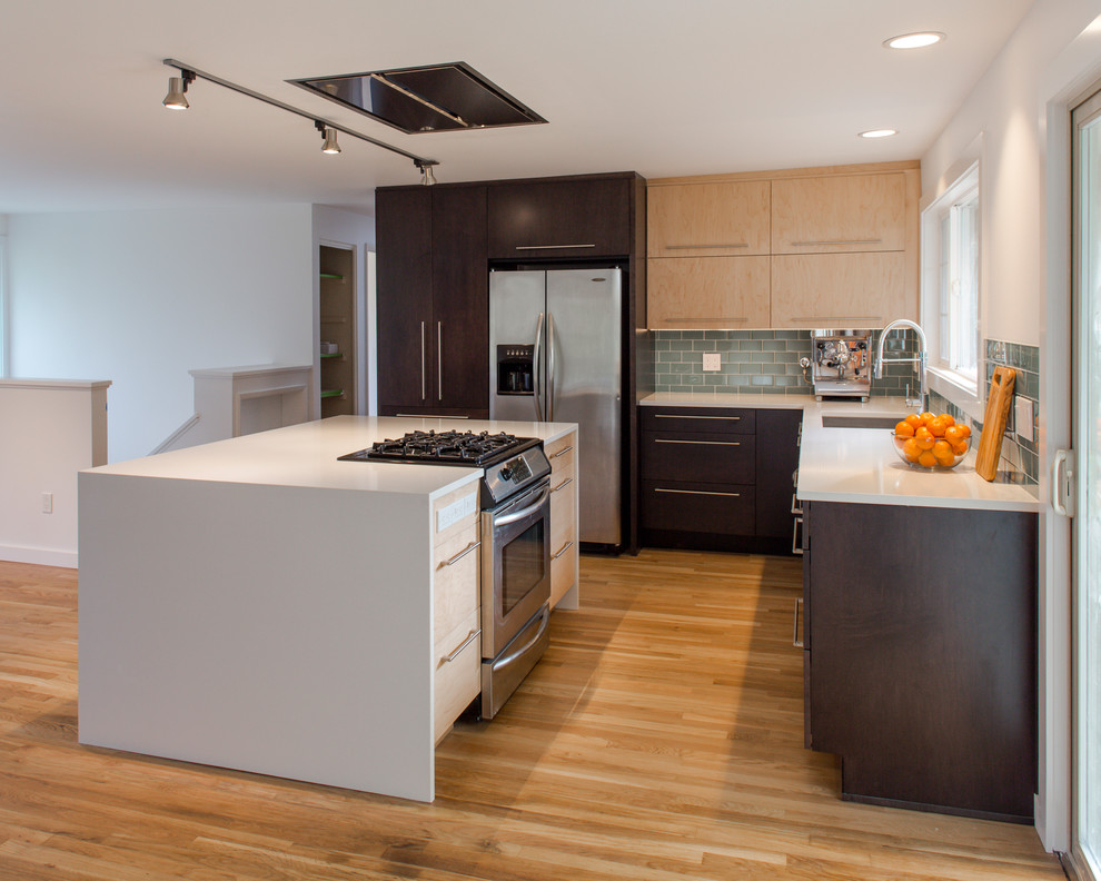 Small modern l-shaped open plan kitchen in Seattle with an undermount sink, flat-panel cabinets, dark wood cabinets, quartz benchtops, green splashback, glass tile splashback, stainless steel appliances, light hardwood floors, with island and yellow floor.