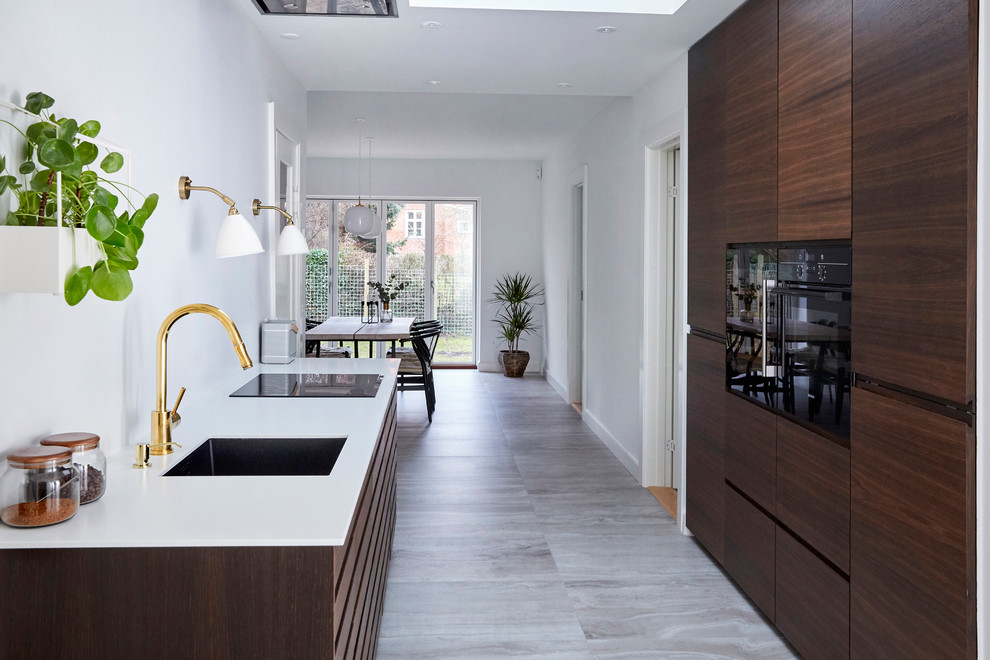 Photo of a mid-sized modern galley open plan kitchen in Copenhagen with an undermount sink, flat-panel cabinets, dark wood cabinets, black appliances, ceramic floors, a peninsula and grey floor.