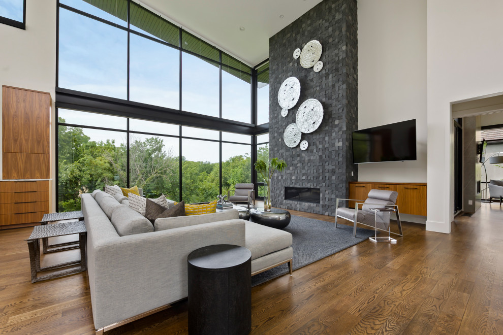 This is an example of a contemporary open concept living room in Houston with white walls, medium hardwood floors, a ribbon fireplace, a stone fireplace surround and brown floor.