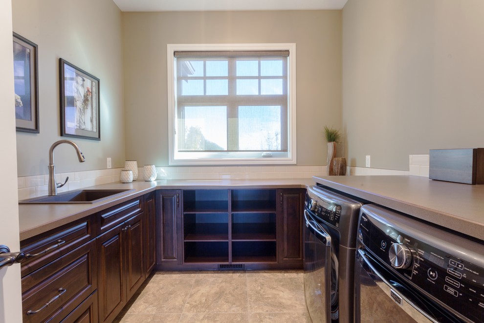 Mid-sized traditional u-shaped dedicated laundry room in Calgary with a drop-in sink, raised-panel cabinets, dark wood cabinets, laminate benchtops, beige walls and a side-by-side washer and dryer.