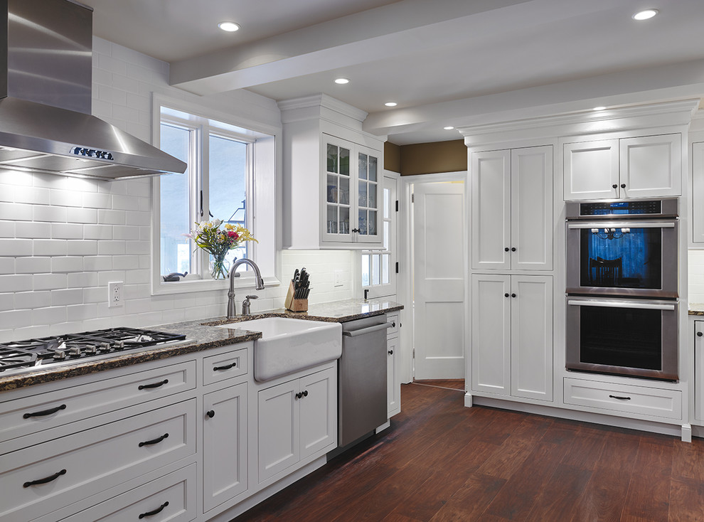 This is an example of a large transitional u-shaped separate kitchen in Philadelphia with a farmhouse sink, shaker cabinets, yellow cabinets, granite benchtops, white splashback, subway tile splashback, stainless steel appliances, dark hardwood floors, brown floor and no island.