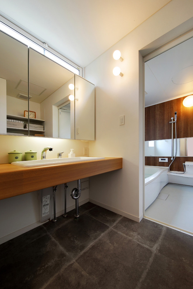 Photo of an industrial bathroom in Other with white walls, vinyl floors, wood benchtops, a drop-in sink, grey floor and brown benchtops.