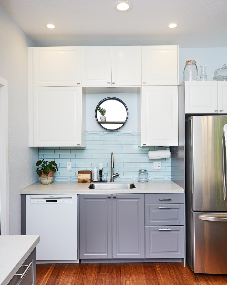 Mid-sized transitional u-shaped bamboo floor and brown floor eat-in kitchen photo with an undermount sink, raised-panel cabinets, gray cabinets, quartzite countertops, blue backsplash, subway tile backsplash, stainless steel appliances, a peninsula and white countertops