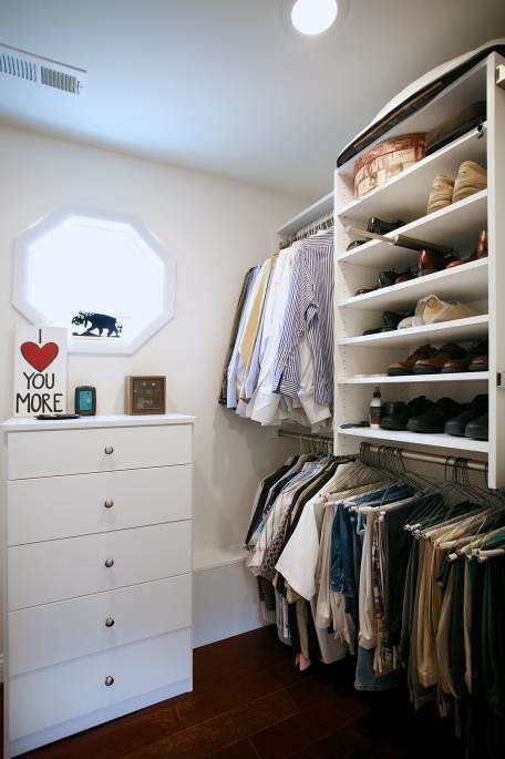 This is an example of a mid-sized traditional men's walk-in wardrobe in Atlanta with dark hardwood floors, flat-panel cabinets, white cabinets and brown floor.