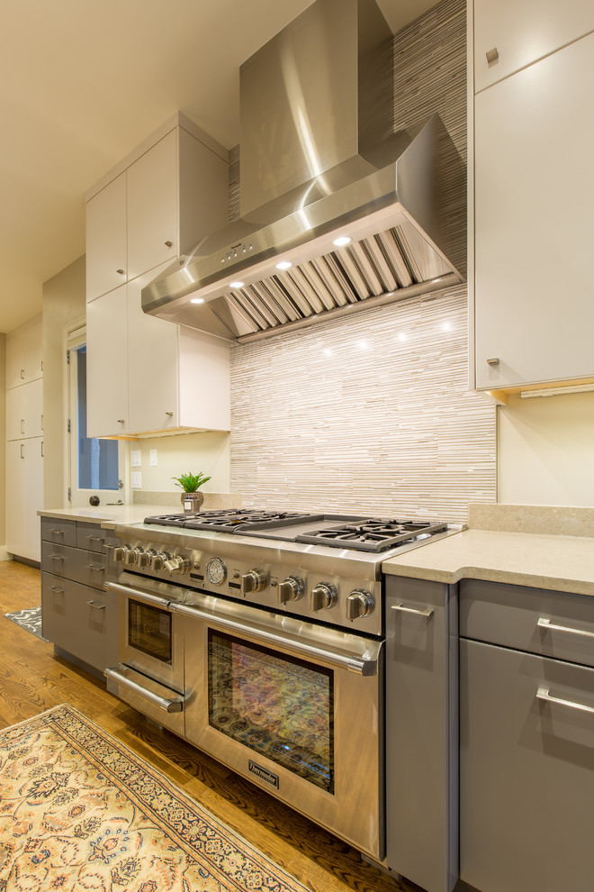 Mid-sized modern galley eat-in kitchen in Austin with an undermount sink, flat-panel cabinets, grey cabinets, soapstone benchtops, multi-coloured splashback, mosaic tile splashback, stainless steel appliances, light hardwood floors and with island.