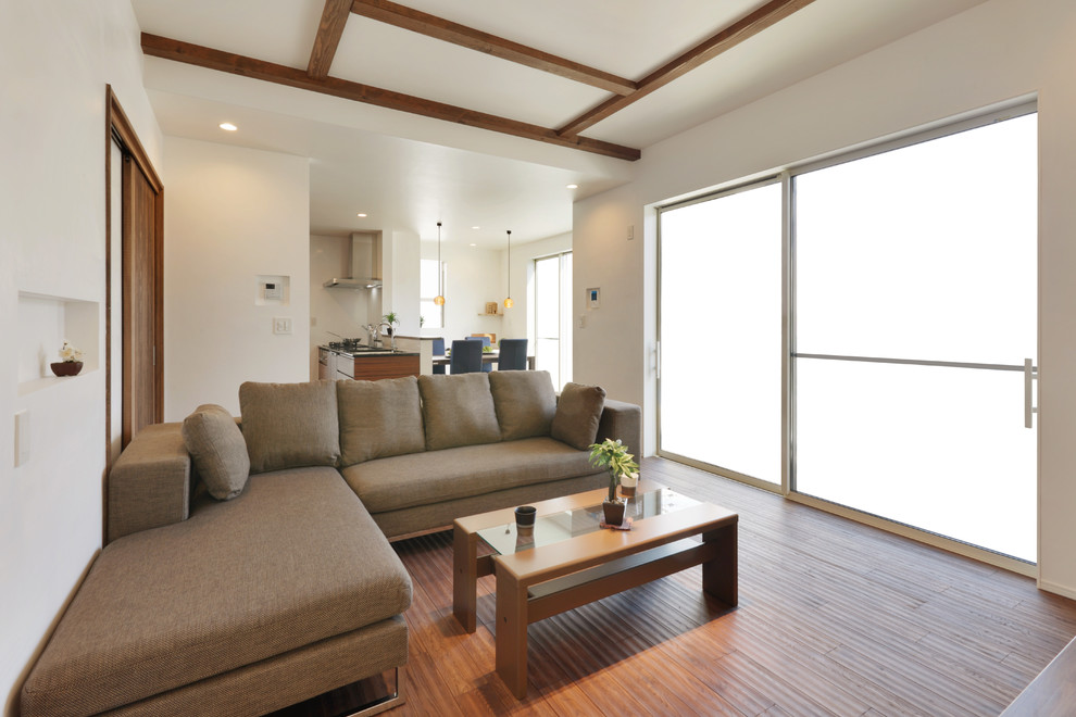 This is an example of an asian open concept living room in Other with white walls, medium hardwood floors and brown floor.