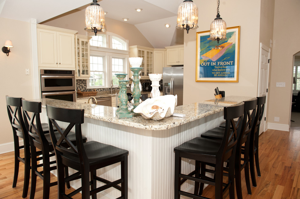 Example of a large transitional light wood floor open concept kitchen design with an undermount sink, raised-panel cabinets, beige cabinets, granite countertops, multicolored backsplash, mosaic tile backsplash, stainless steel appliances and a peninsula