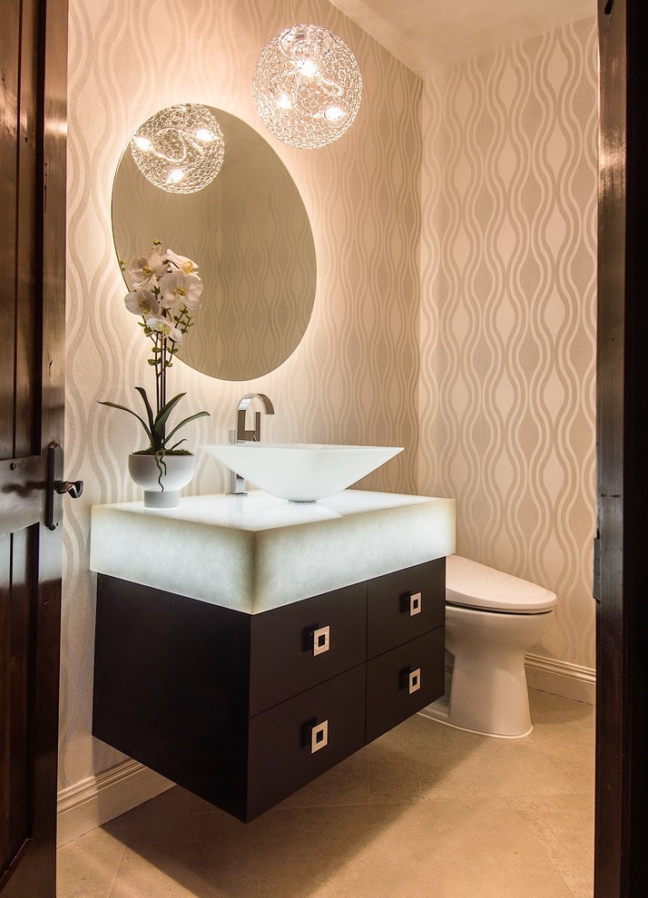 Photo of a mid-sized contemporary powder room in Los Angeles with flat-panel cabinets, dark wood cabinets, a two-piece toilet, white tile, travertine floors, a vessel sink, glass benchtops, beige walls and white benchtops.