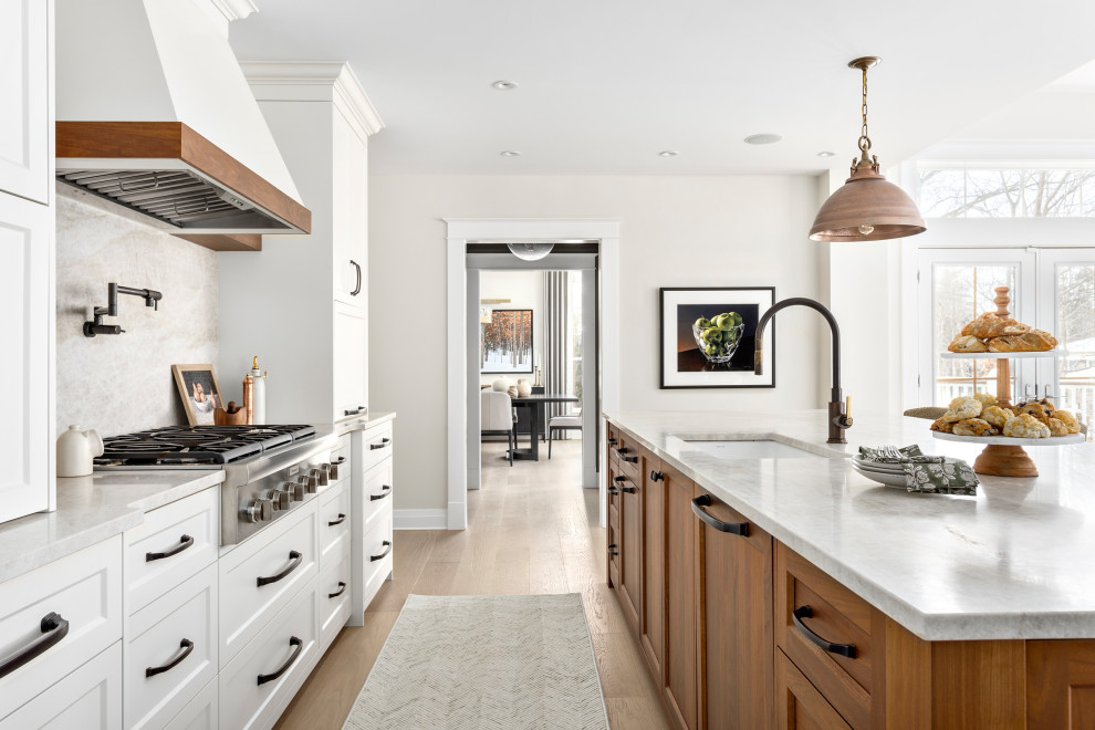 Example of a large transitional l-shaped medium tone wood floor and brown floor open concept kitchen design in Other with an undermount sink, shaker cabinets, quartz countertops, multicolored backsplash, quartz backsplash, stainless steel appliances, an island, beige countertops and white cabinets