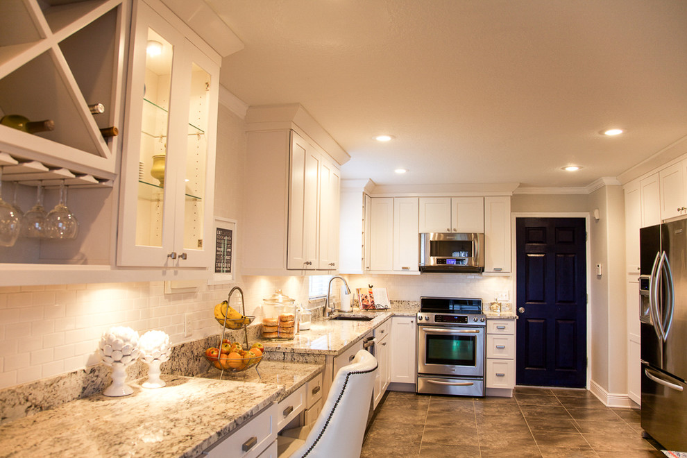 This is an example of a large transitional l-shaped eat-in kitchen in Tampa with an undermount sink, shaker cabinets, white cabinets, granite benchtops, white splashback, subway tile splashback, stainless steel appliances and porcelain floors.