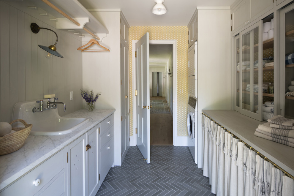 Immagine di una sala lavanderia con lavatrice e asciugatrice a colonna, pavimento grigio e lavello da incasso