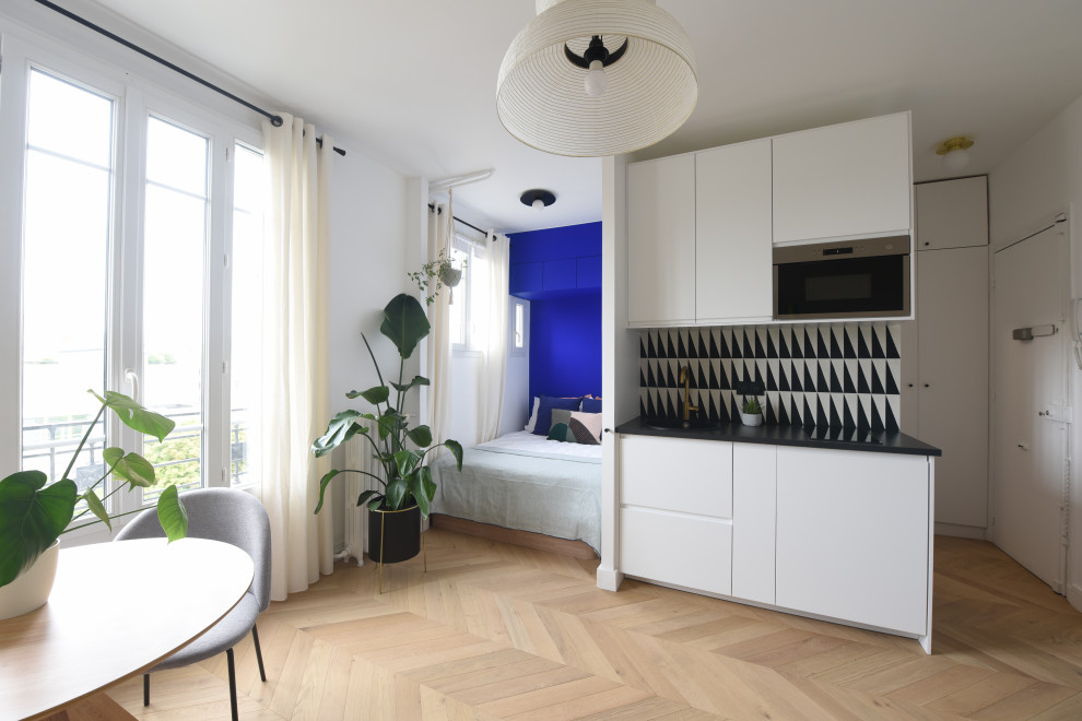 Photo of a small contemporary single-wall kitchen in Paris with a single-bowl sink, laminate benchtops, multi-coloured splashback, cement tile splashback, laminate floors, no island and black benchtop.