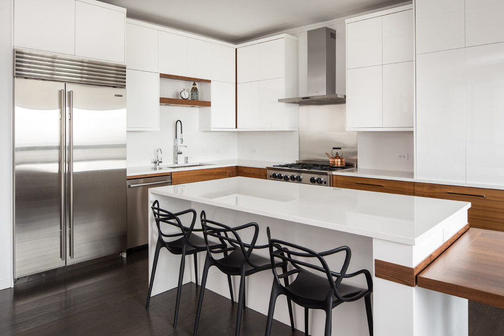 This is an example of a contemporary l-shaped kitchen in Chicago with an undermount sink, flat-panel cabinets, white cabinets, white splashback, stainless steel appliances, dark hardwood floors and with island.