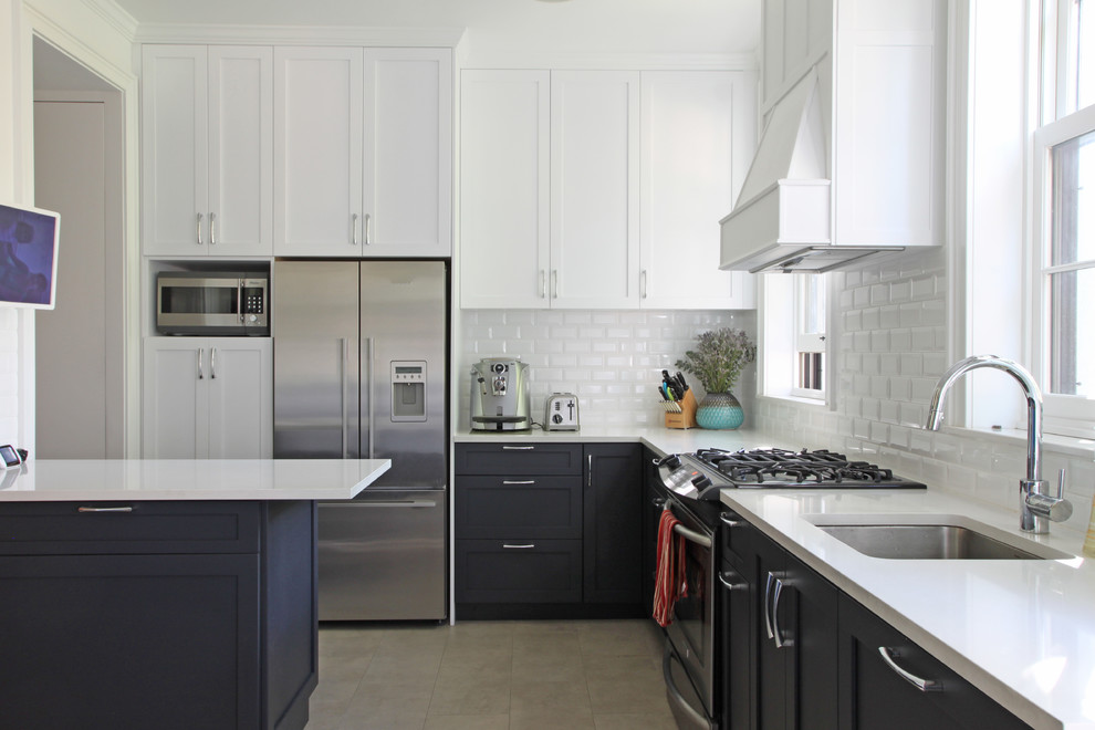 This is an example of a transitional l-shaped kitchen in New York with an undermount sink, shaker cabinets, white cabinets, white splashback, subway tile splashback and stainless steel appliances.