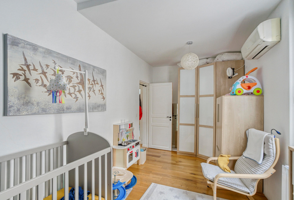Réalisation d'une chambre d'enfant de 1 à 3 ans design de taille moyenne avec un mur bleu, parquet clair et un sol marron.