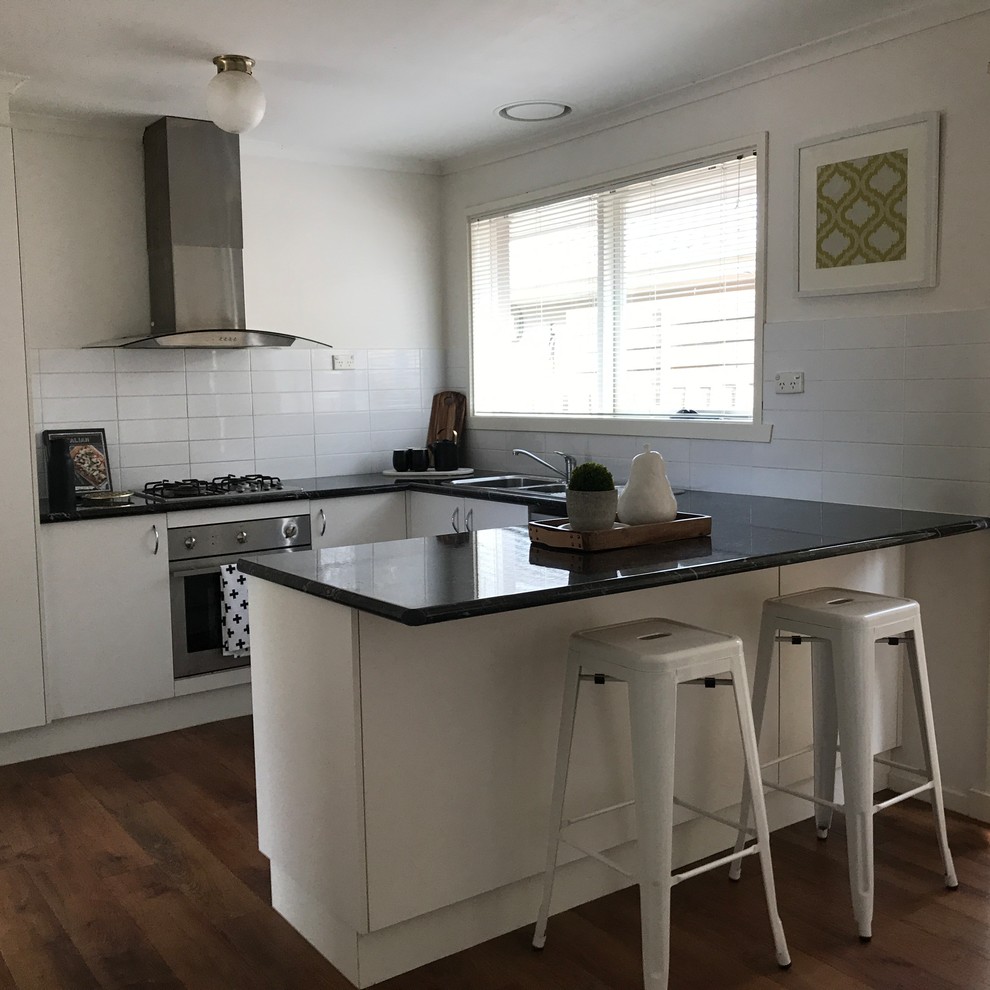 Inspiration for a small contemporary u-shaped eat-in kitchen in Geelong with a double-bowl sink, flat-panel cabinets, white cabinets, marble benchtops, white splashback, subway tile splashback, stainless steel appliances, a peninsula and medium hardwood floors.